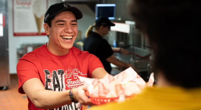 Freddy's employee handing food to customer